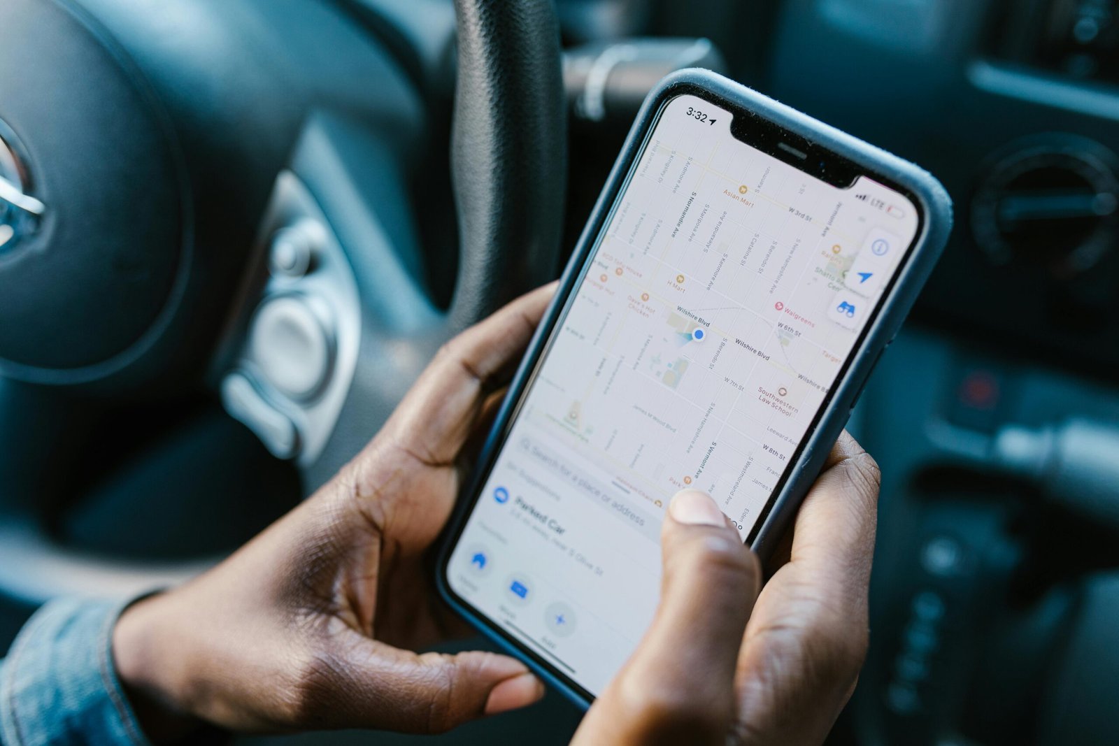 Driver of a car looking at a map on a cell phone.