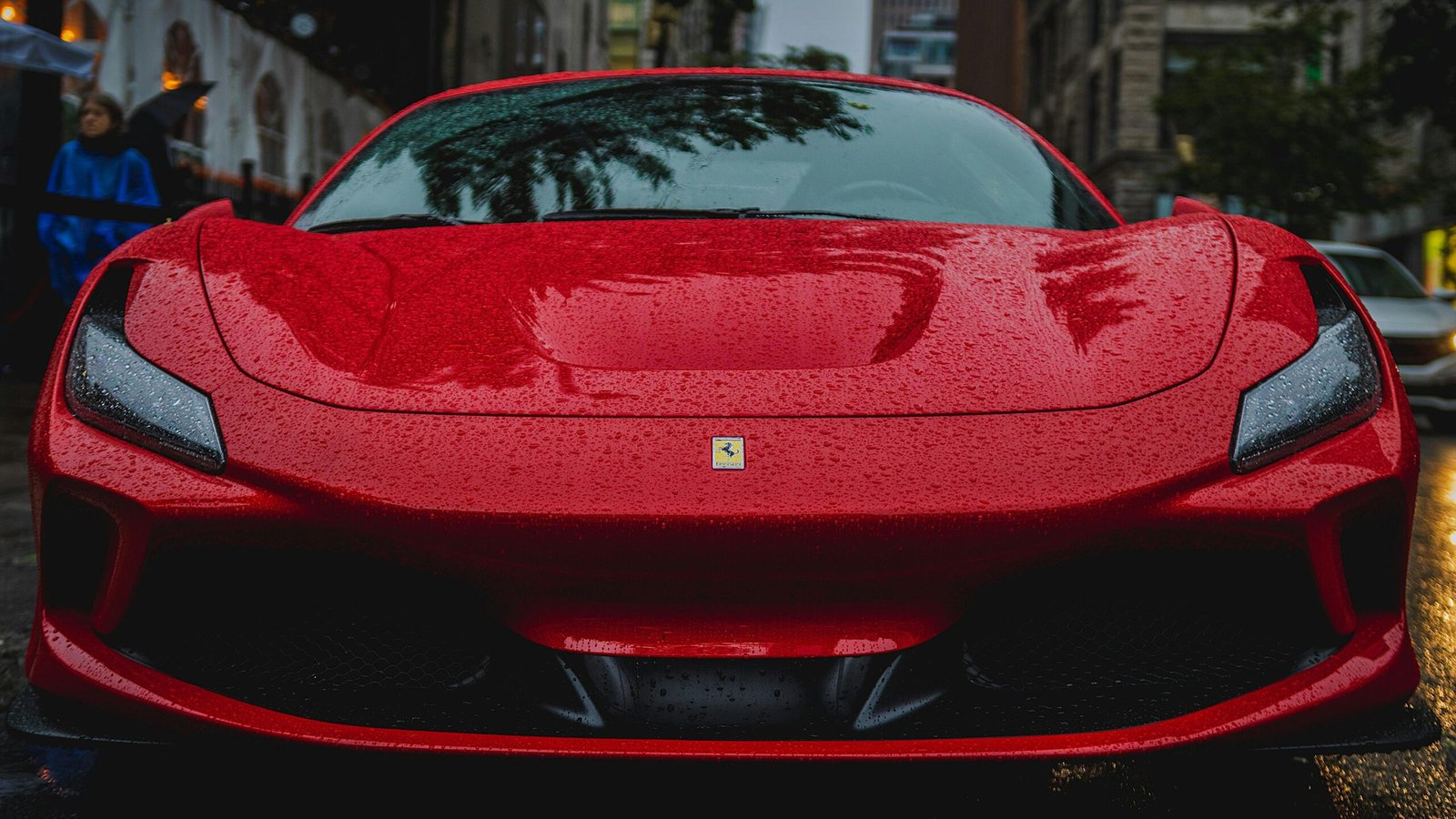 The front of a parked, red Ferrari sports car in the rain.